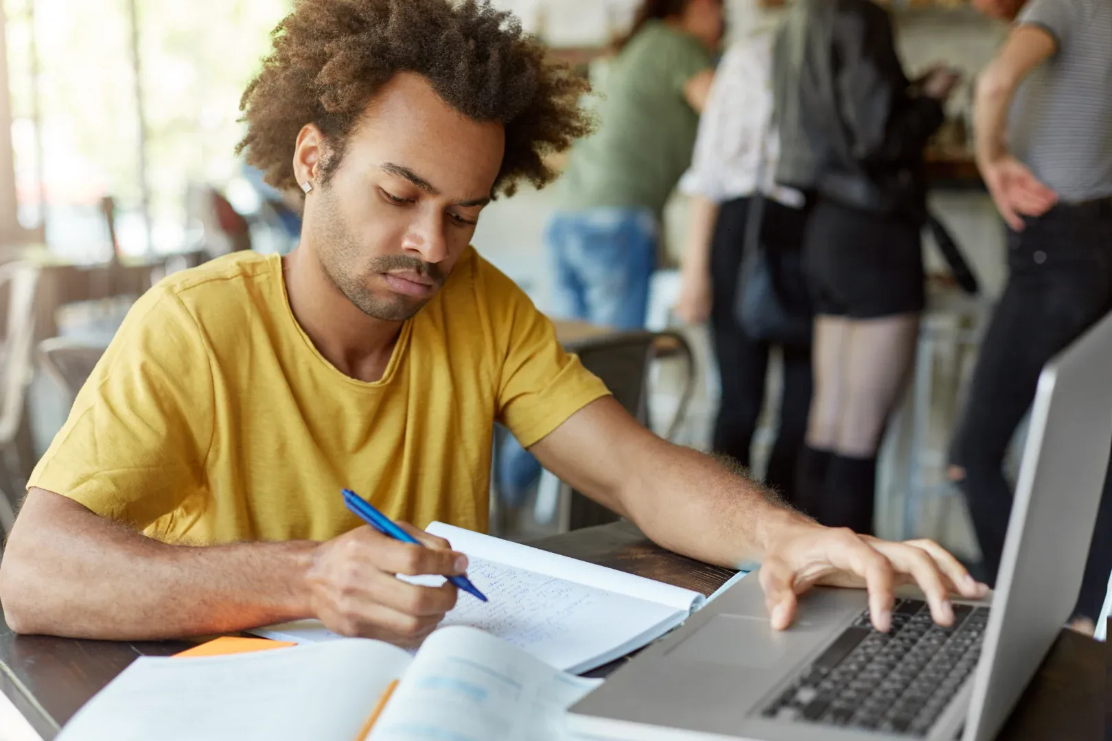 Tema de TCC: como escolher o seu durante a graduação online? | Foto de um jovem com expressão séria enquanto faz trabalho da faculdade | UNIFAVENI