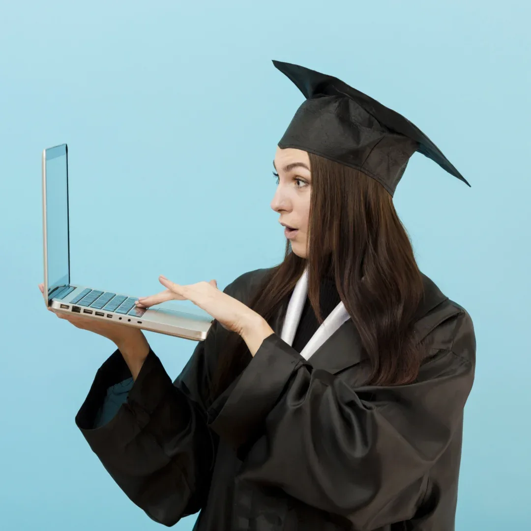 Graduação EaD em 2025: ainda vale a pena? | Jovem mulher surpresa enquanto segura e olha para o notebook, vestida com beca e capelo | UNIFAVENI