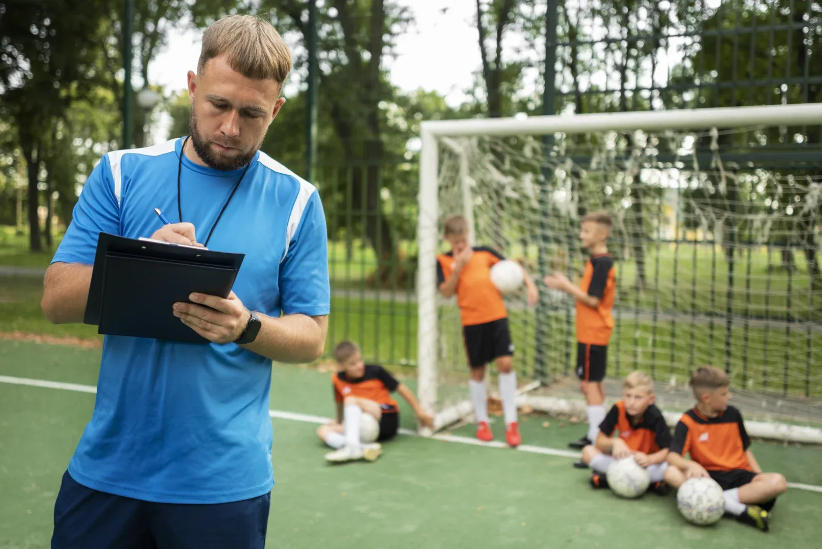 O que preciso saber do curso superior de Educação Física? | Foto de um professor de educação físico com seus alunos na quadra de futebol | UNIFAVENI