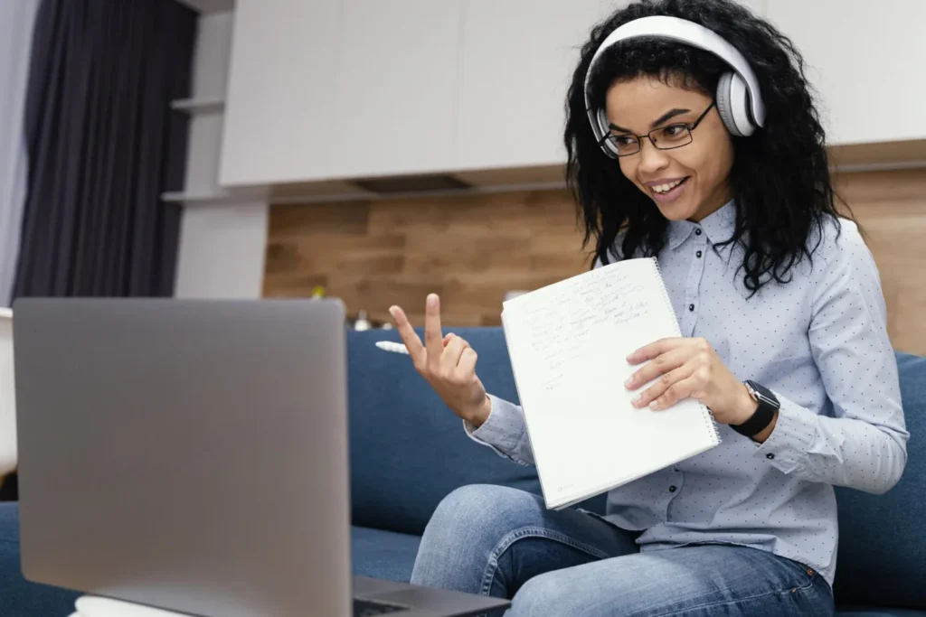 Grupo de estudos na graduação EaD: qual é a importância? | Foto de jovem mulher com fones de ouvido conversando em uma reunião online | UNIFAVENI