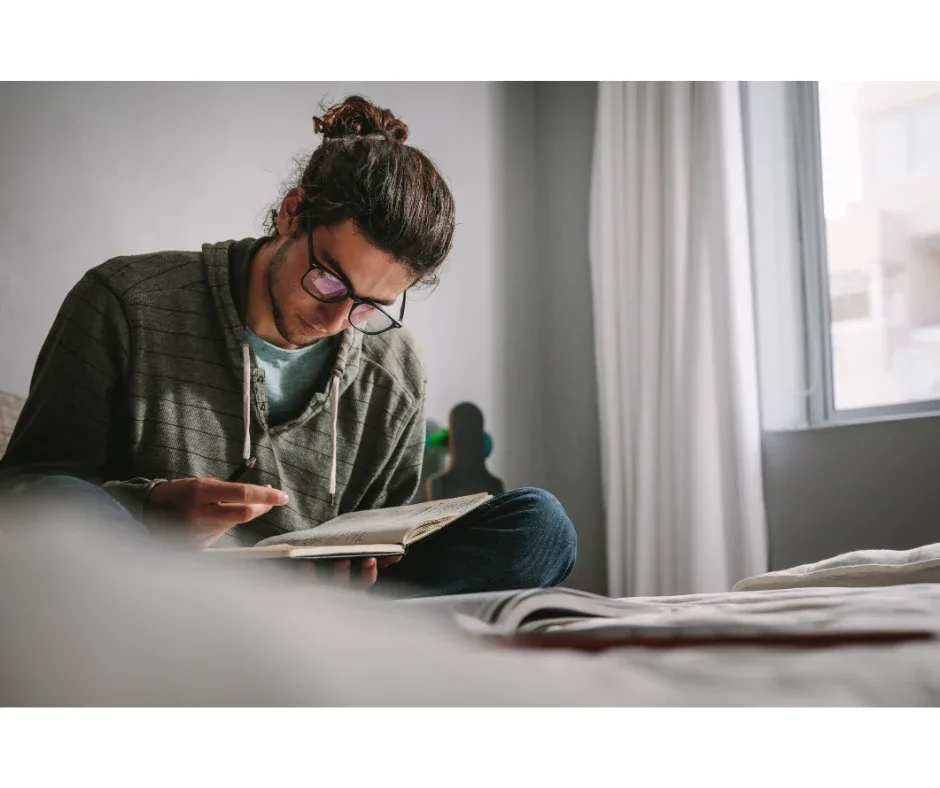 Pesquisa acadêmica na faculdade: como fazer? | Foto de um jovem estudante lendo um livro | UNIFAVENI