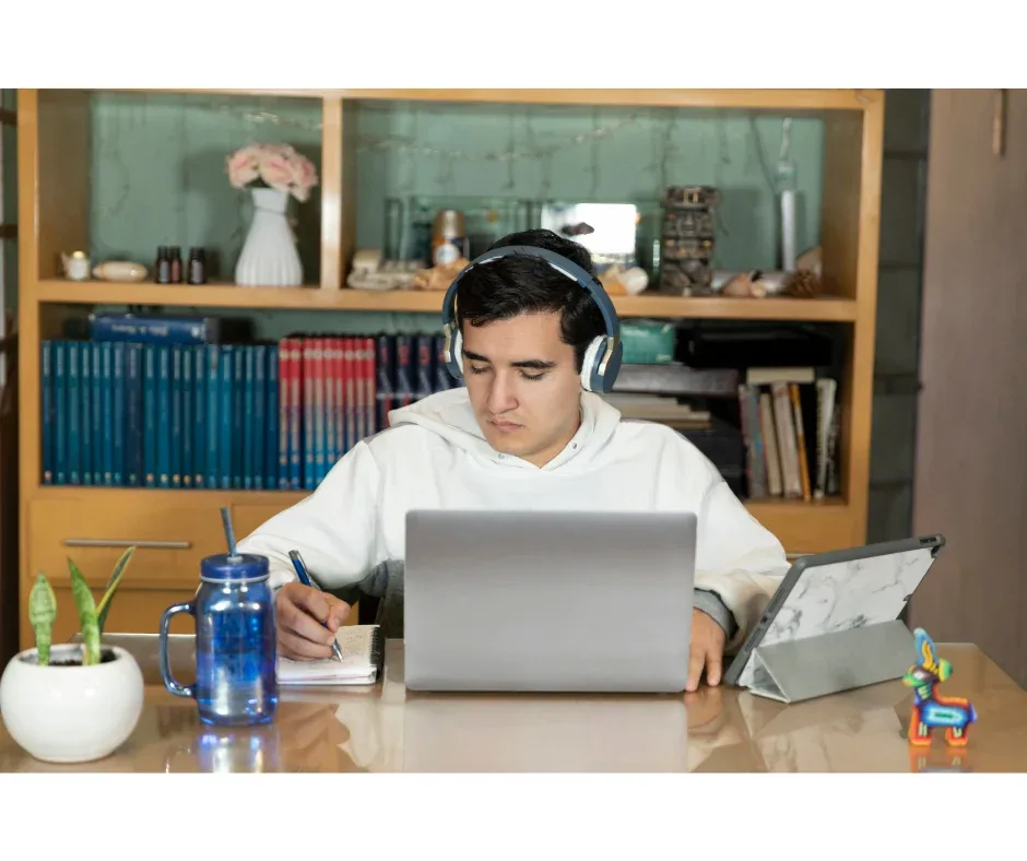 Estudar na graduação EaD: o que usar para ajudar? | Jovem homem de fones de ouvido sentado em uma mesa