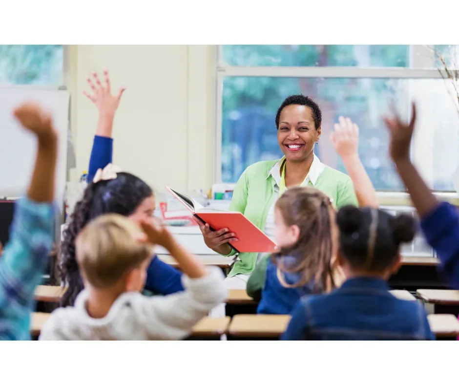 Graduação na área da educação: por que investir nesse setor? | Professora sorrindo em sala de aula enquanto ensina aos alunos | UNIFAVENI||Graduação na área da educação: por que investir nesse setor? | Professora sorridente agachada em frente mesa de aluna para ajuda-la | UNIFAVENI